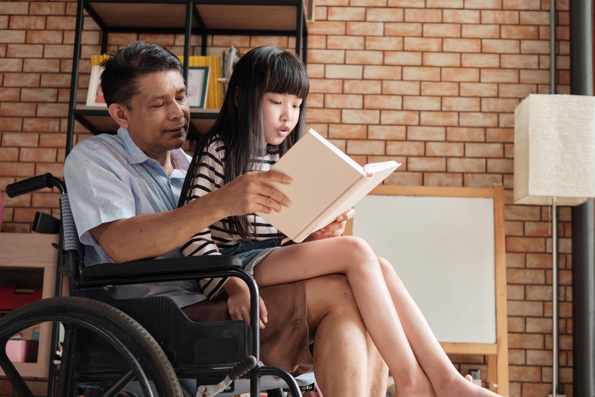 Person and child reading in book a wheelchair