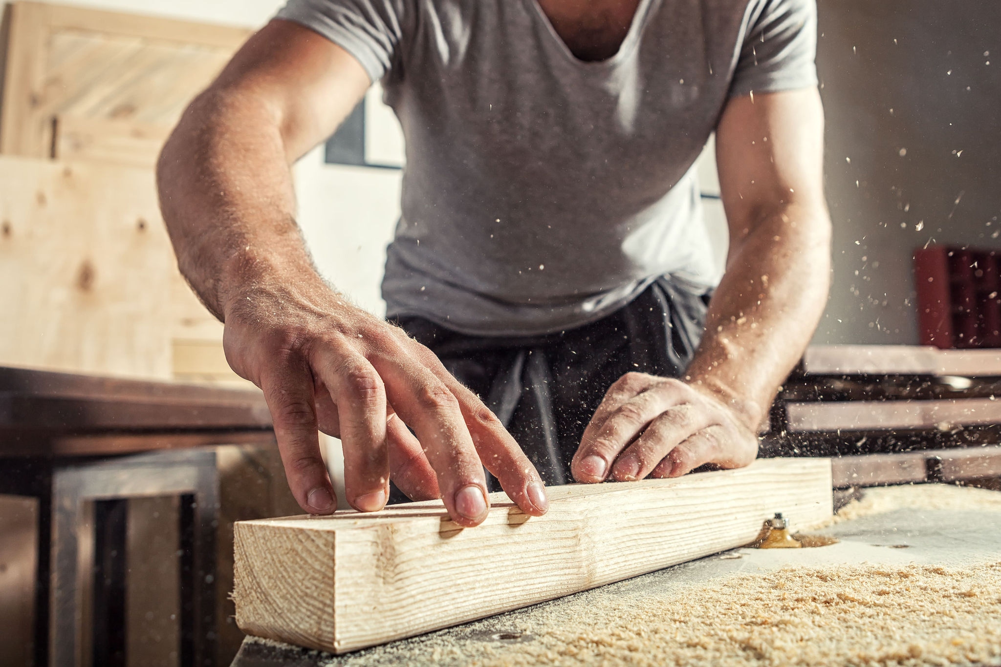 Close up of a person holding a piece of timer and using an electric tool