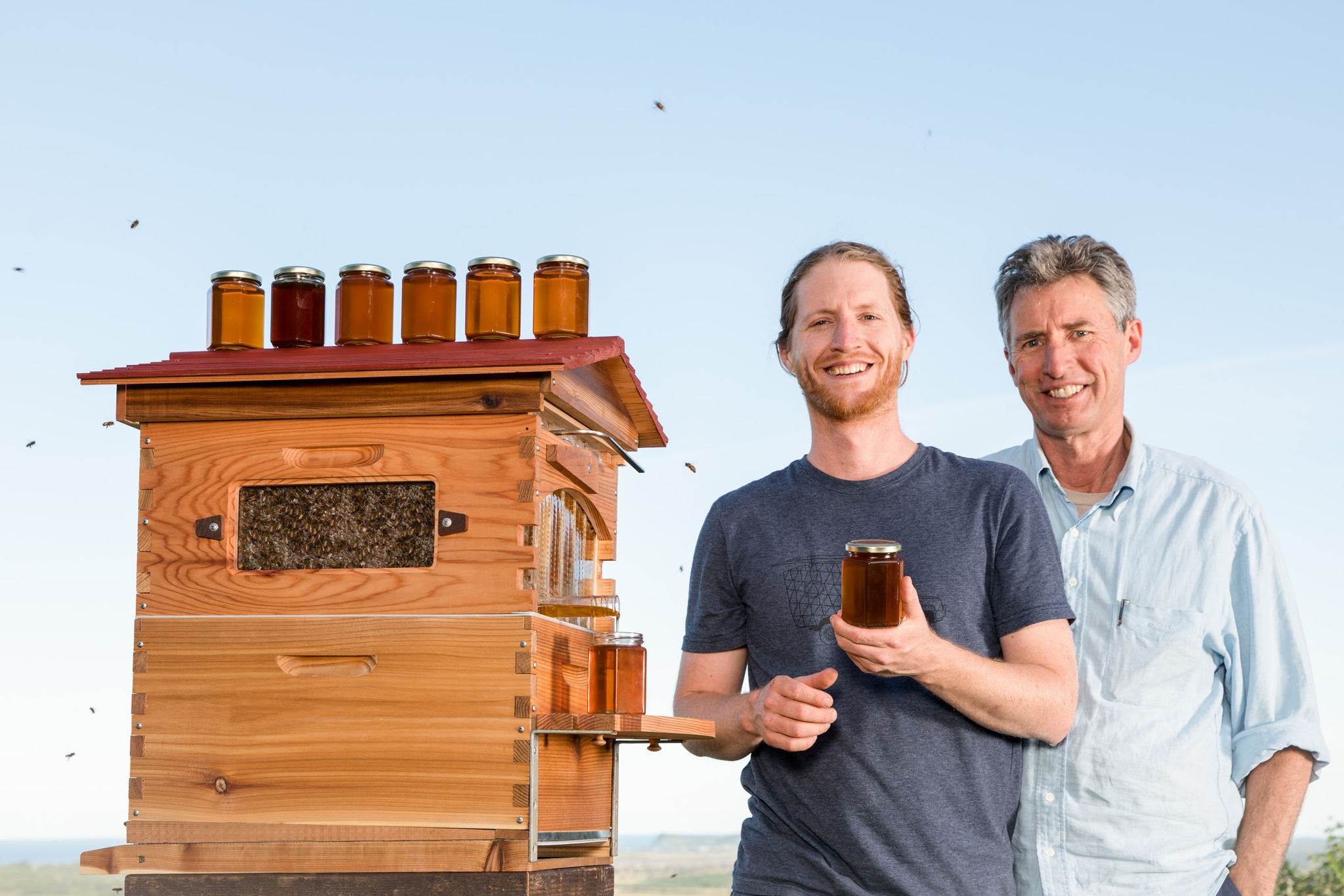 2 people with a bee hive and honey