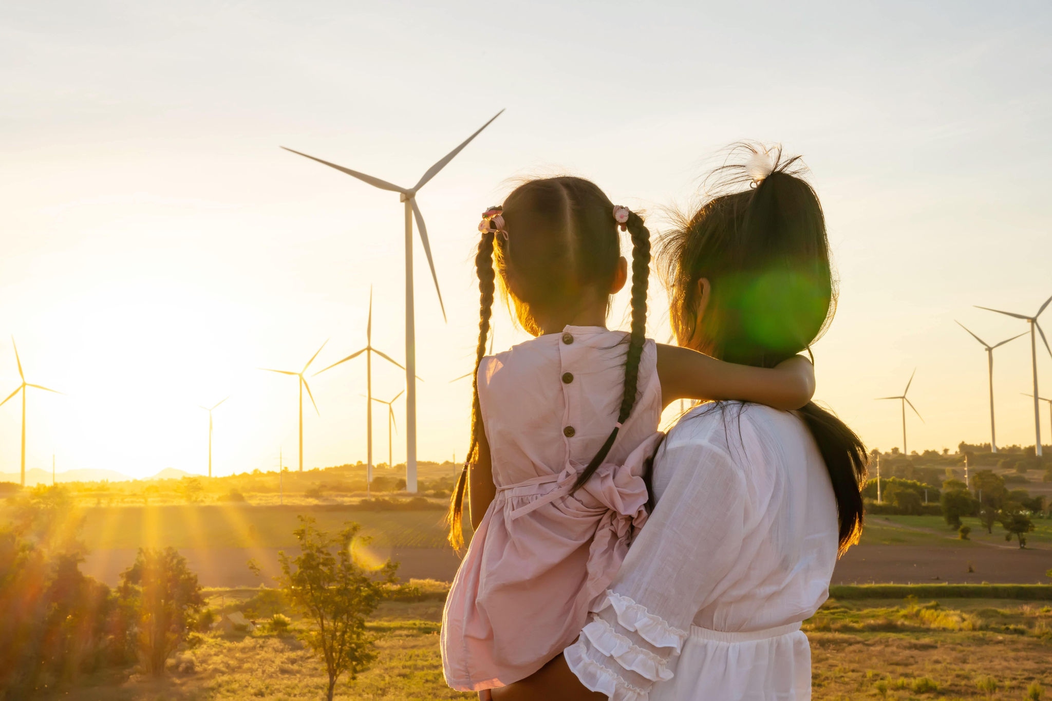 Parent holding a child near a wind turbine