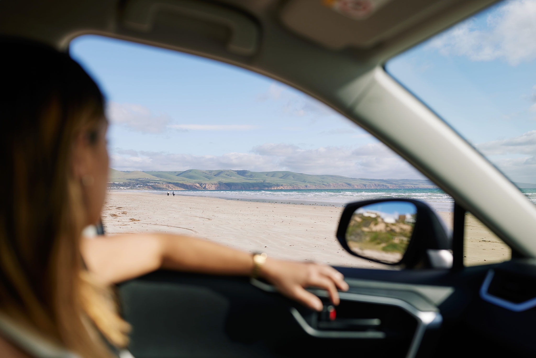 Person in a car, looking out the window at a coastal scene