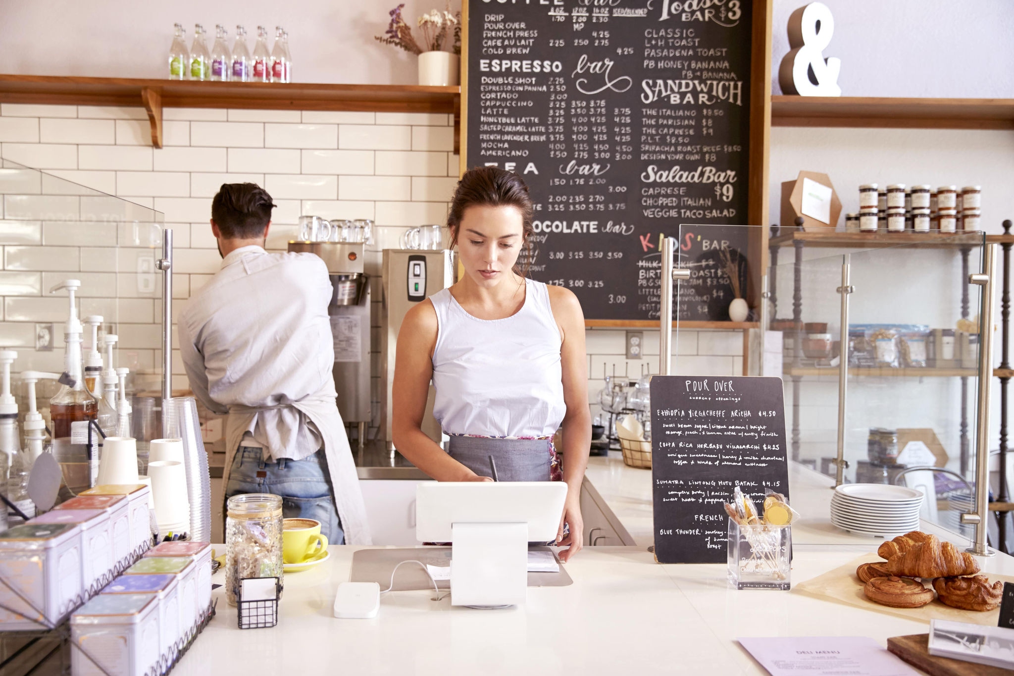 2 people working in a café' on on register one making coffee