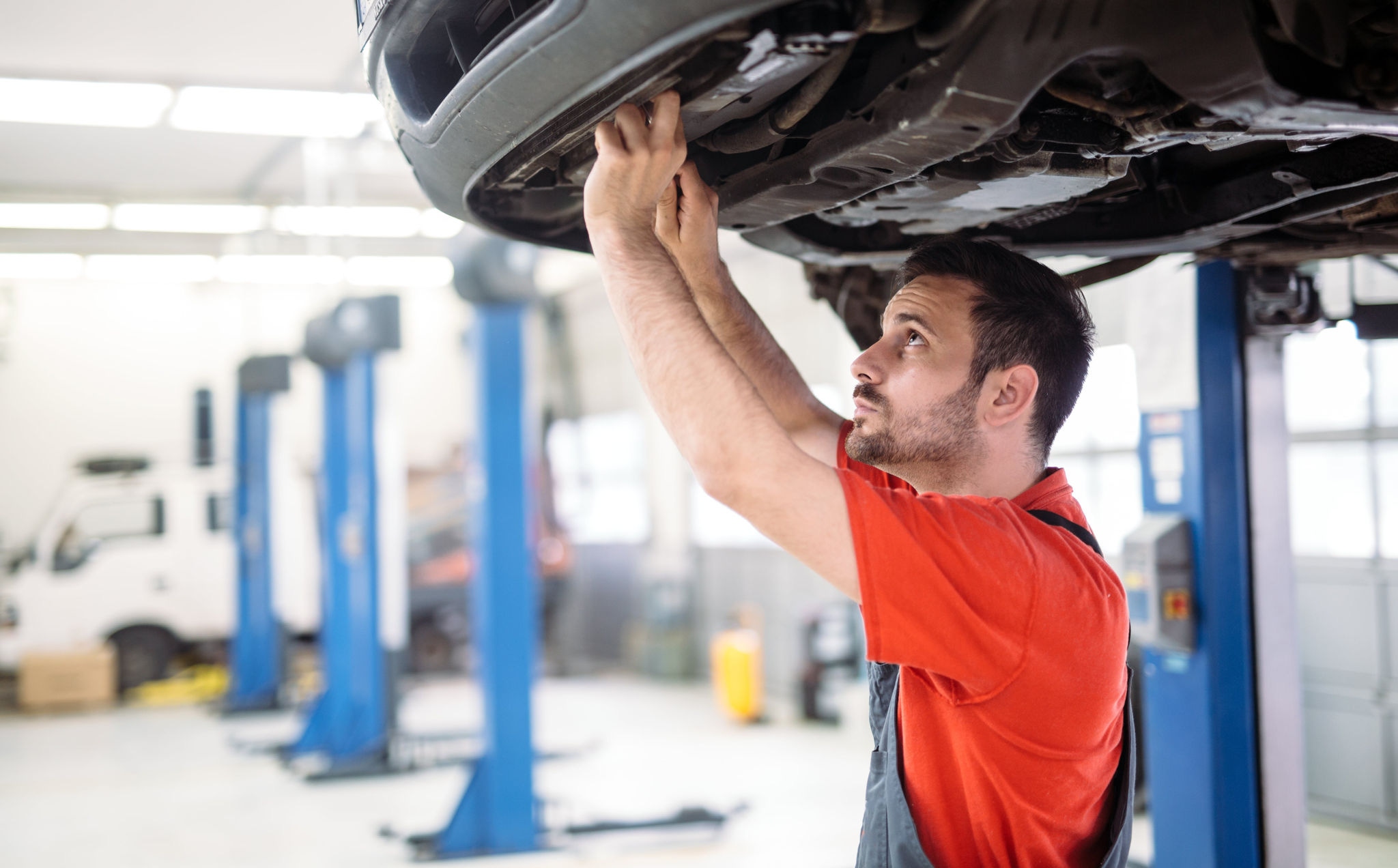 Mechanic looking at a car on a hoist from underneath