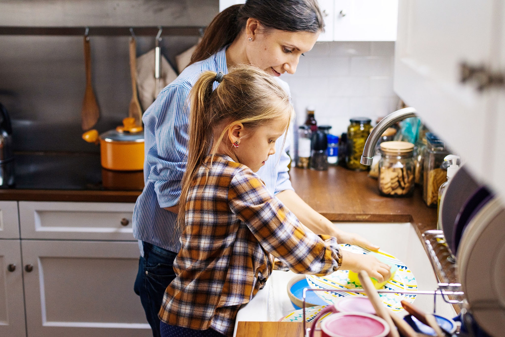 Parent and child at sink washing dishes